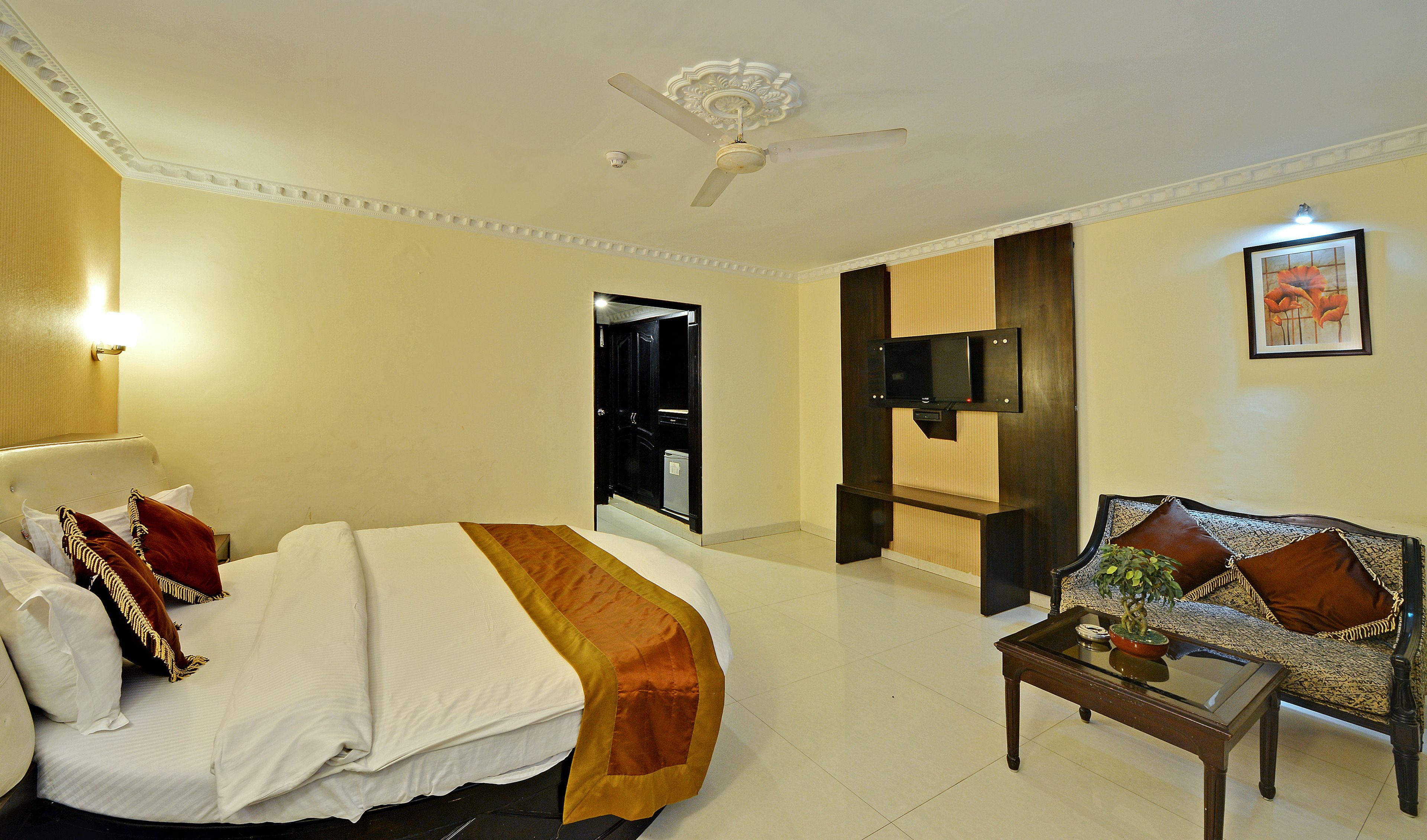 Ein Hotelzimmer mit Bett, Sofa, Fernseher und Deckenventilator.