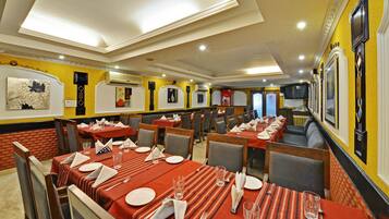 A restaurant with multiple tables set for dining, featuring a brick wall and yellow decor.