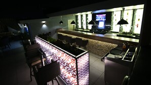 Un espace bar agrémenté d’un luminaire décoratif, de sièges et d’un écran de télévision.