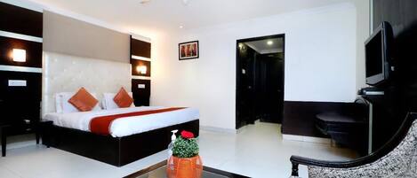 A modern hotel room with a large bed, a sofa, a TV, and a ceiling fan.
