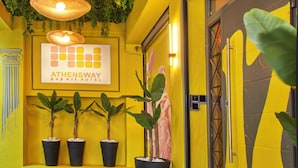 A reception area with a green artificial grass floor, potted plants, and a sign for Athenesway Popas Hotel. - Athens Way Pop Art Hotel (Athens)