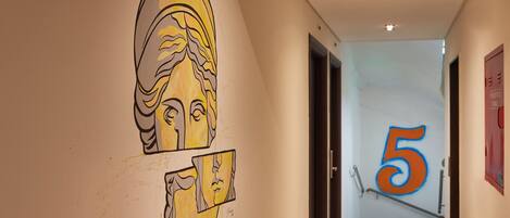A hallway with a wall mural featuring abstract faces and the number 5.