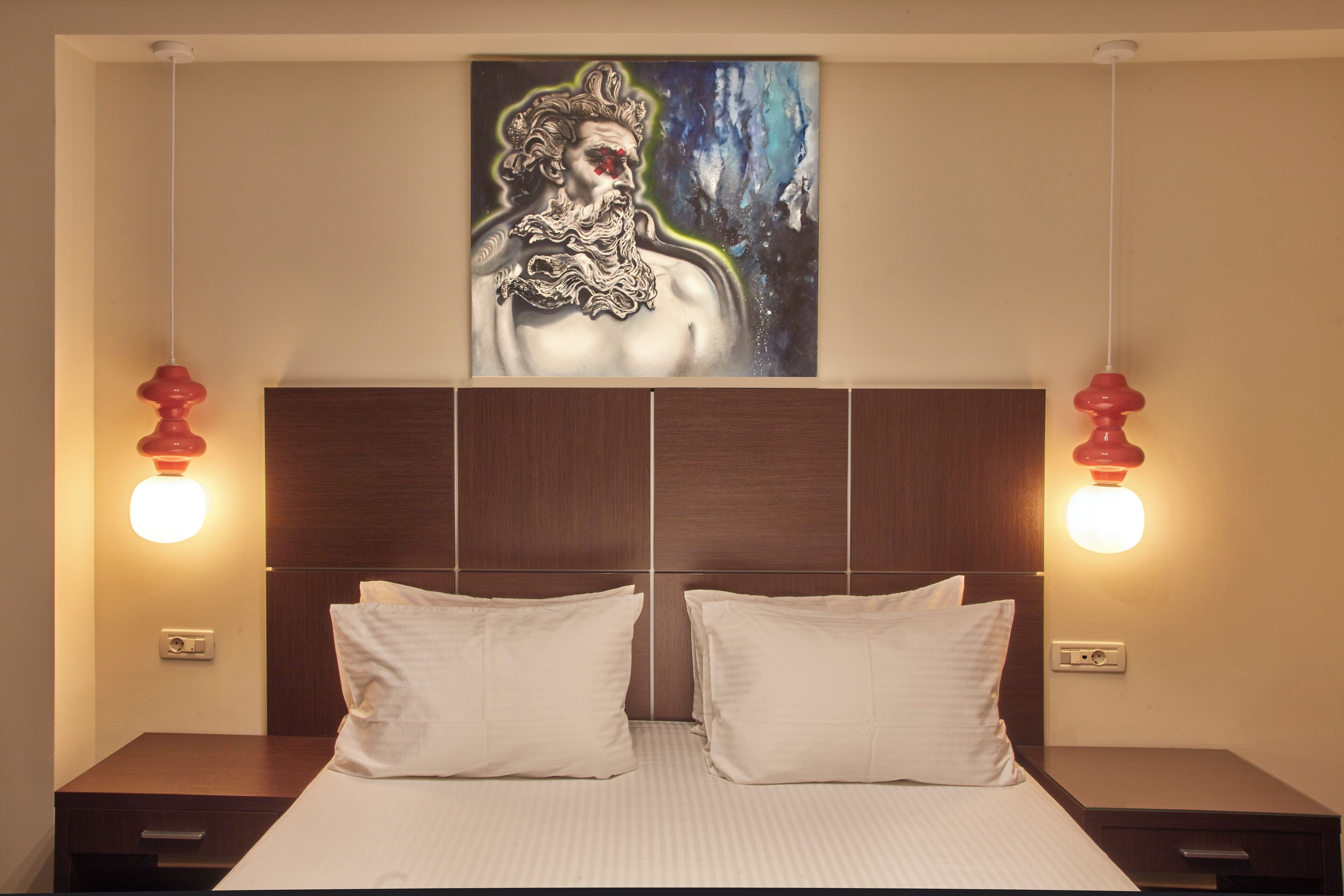 A hotel room with a large bed, two bedside tables, and a wall-mounted painting.