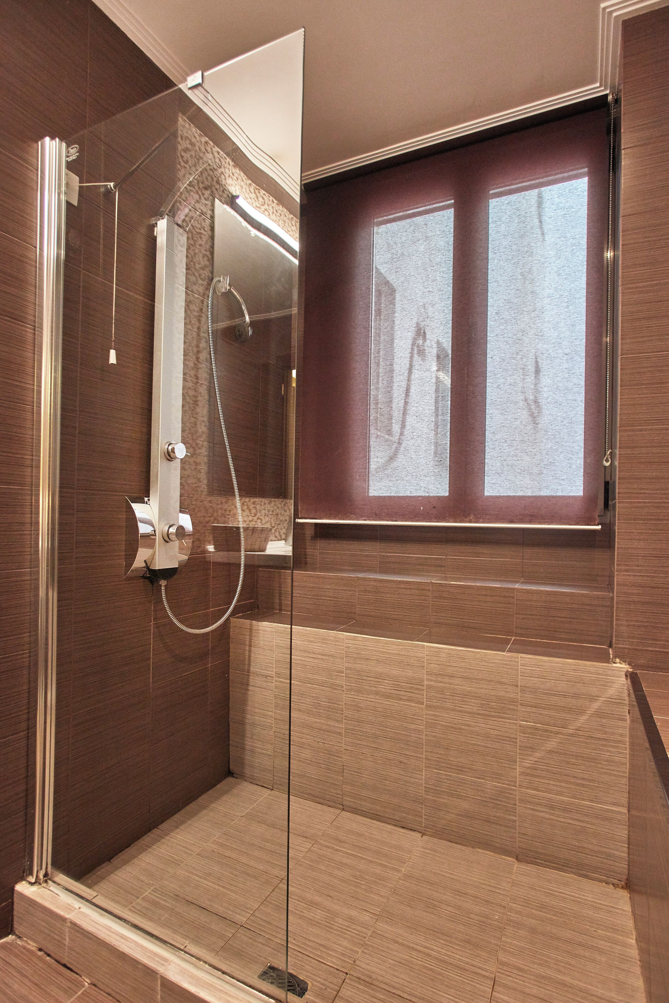A modern bathroom with a glass-enclosed shower, a vanity with a mirror, and a window above the sink.