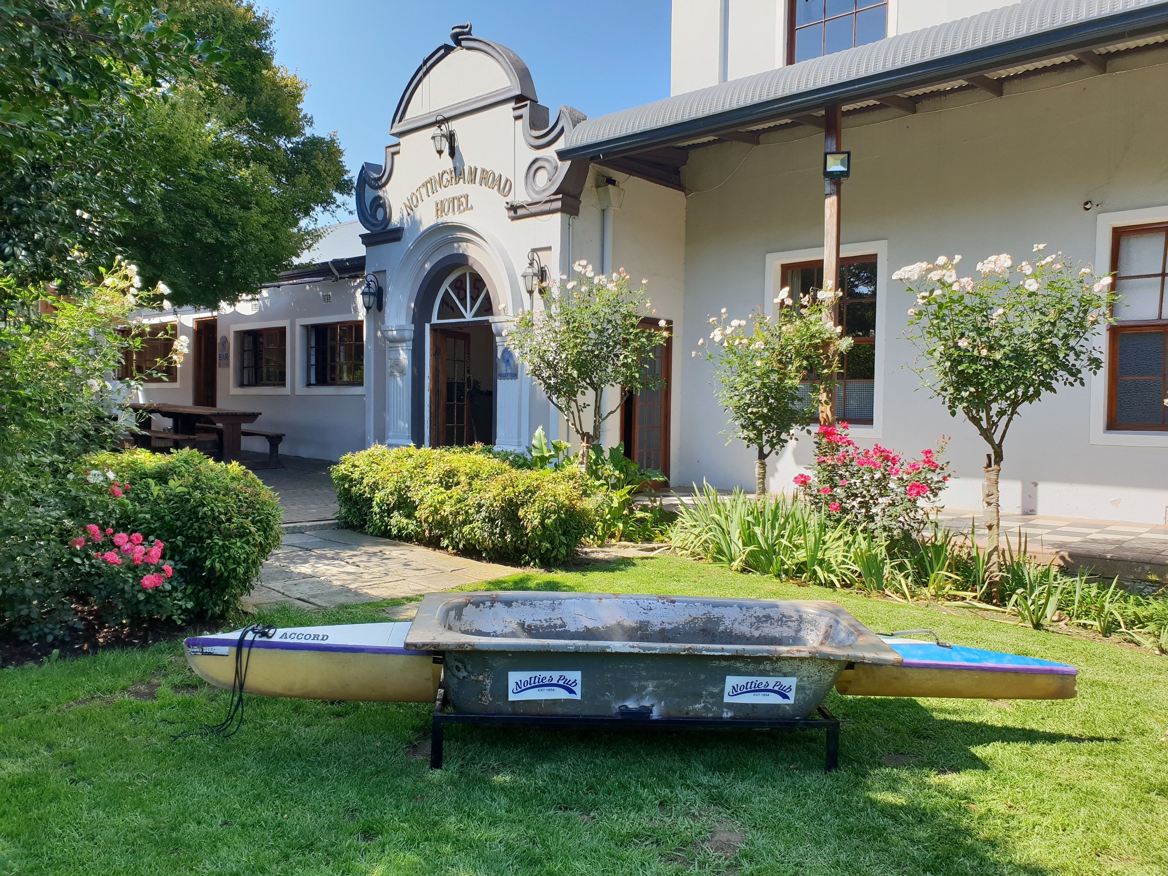 A hotel with a classic facade, a well-maintained garden, and a boat in the foreground.