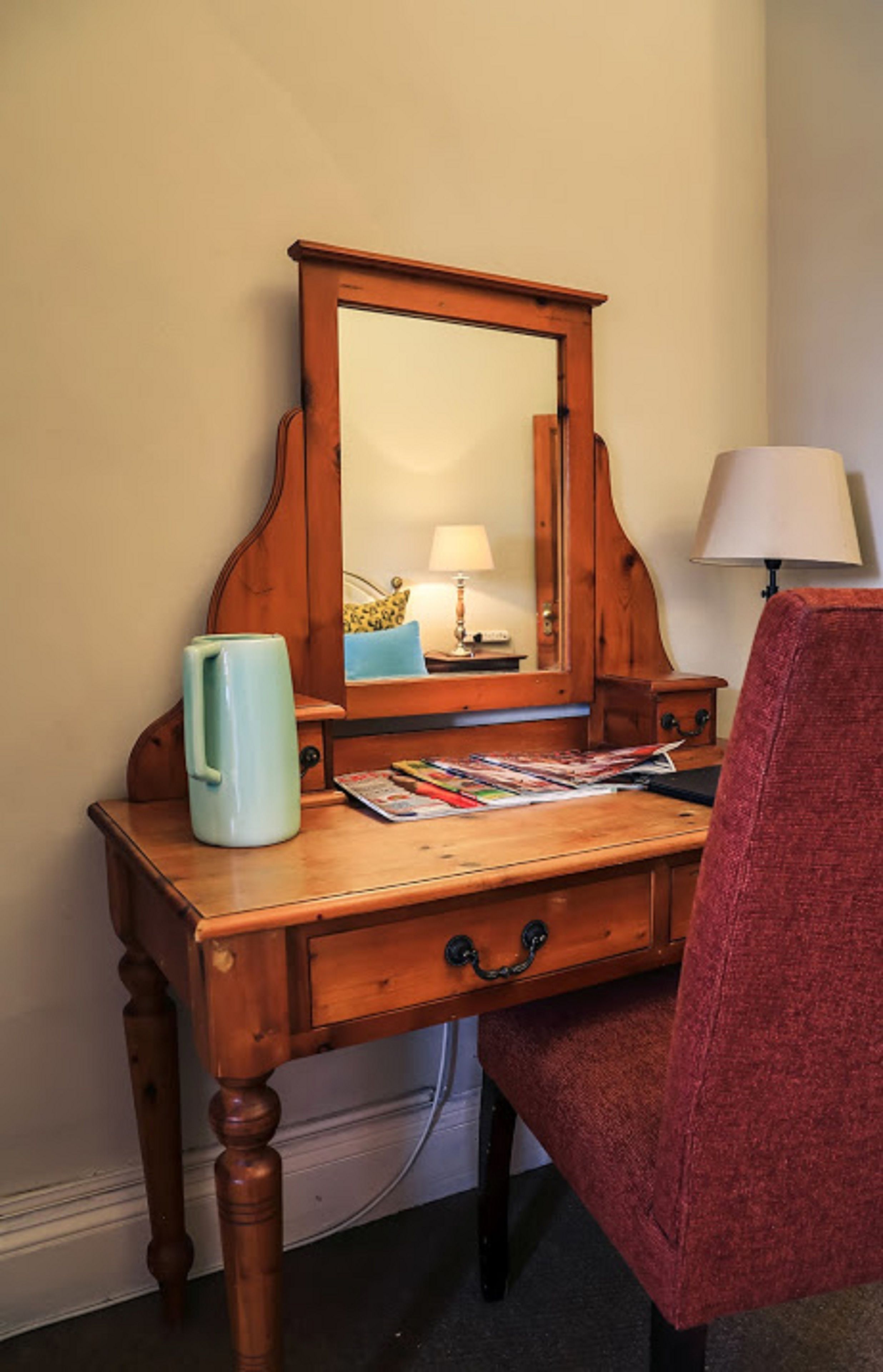 Ein Holztisch mit Spiegel, Lampe und Tasse.