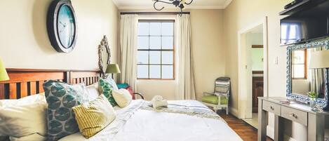 Un dormitorio con una cama grande, una araña, un espejo y una ventana con cortinas.