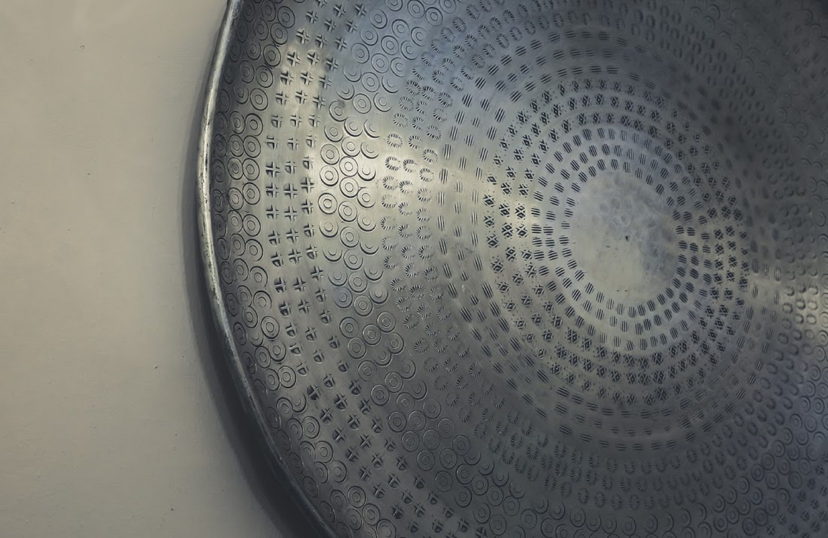 A close-up of a metallic surface with circular patterns and embossed text.
