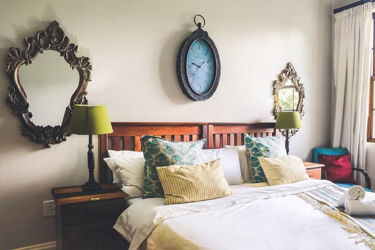 A neatly made bed with a striped blanket, two bedside lamps, and a wall clock.