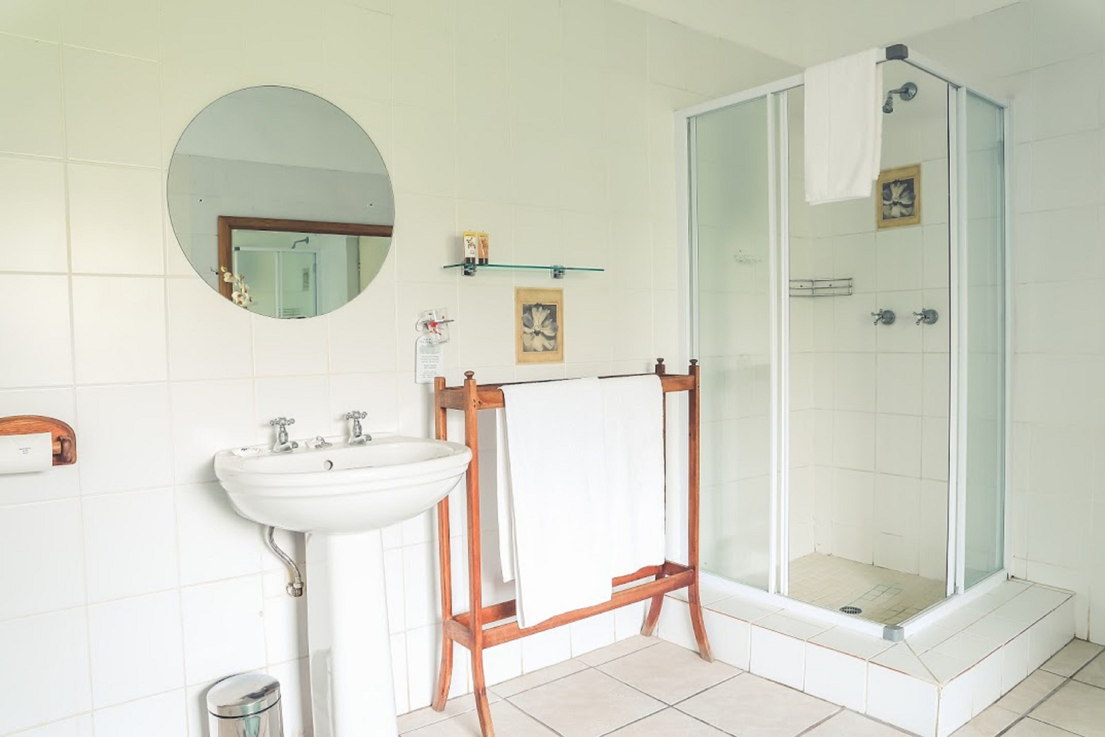 Une salle de bain avec un lavabo blanc, un miroir et une douche à parois de verre.