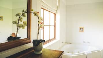 Une salle de bain avec un grand miroir, une baignoire et une fenêtre avec des rideaux.