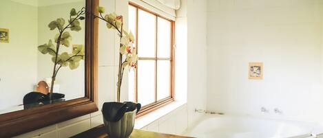 Un baño con un espejo grande, una bañera y una ventana con cortinas.