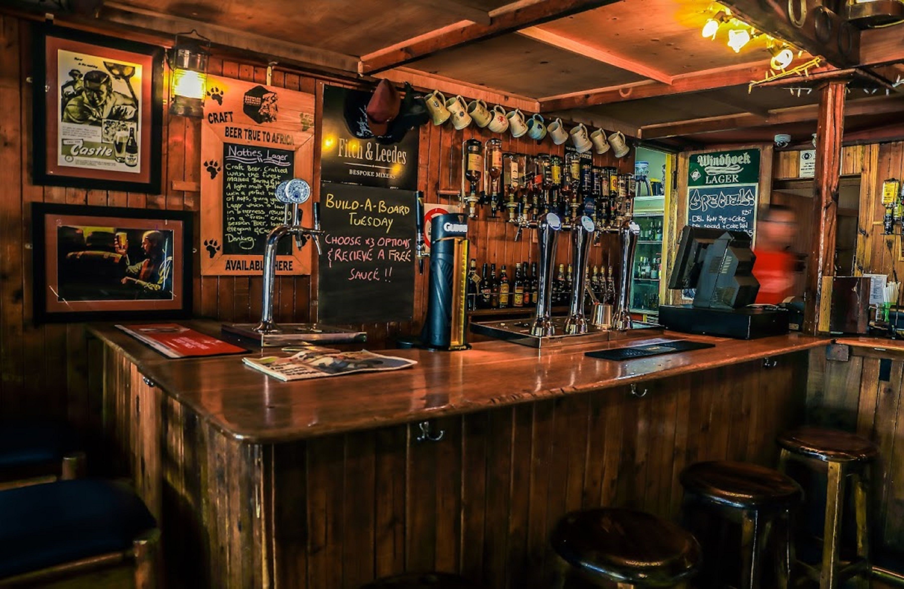 A bar with wooden decor, multiple taps, and a menu board advertising beer options.