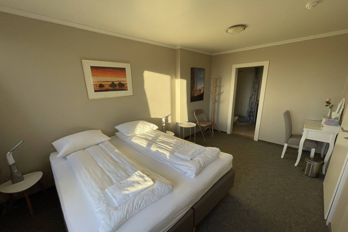 Una habitación de hotel con cama doble, un escritorio, una silla y una mesita.