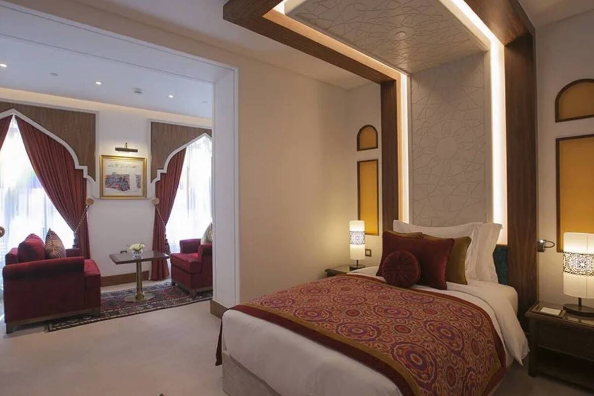 Une chambre d’hôtel dotée d’un grand lit, d’un coin salon avec un canapé et un fauteuil, ainsi que d’un espace repas séparé avec une table et des chaises.