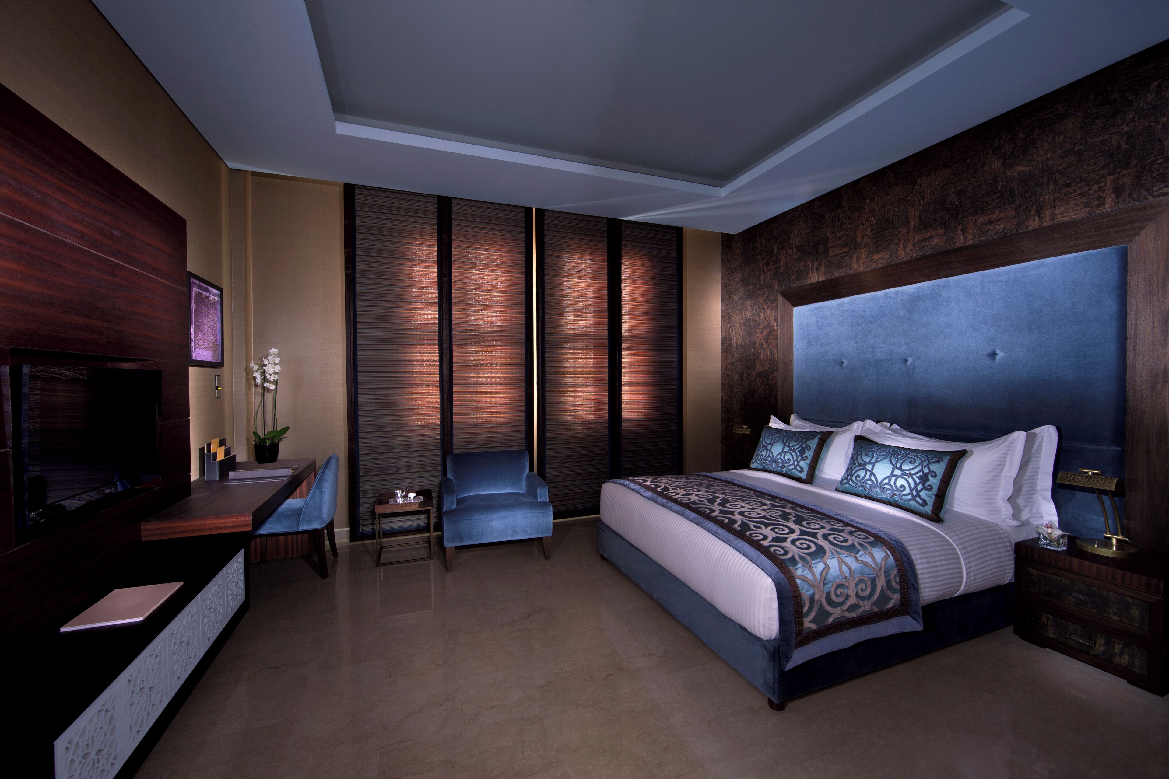 A modern hotel room with a large bed, a desk, and a seating area.