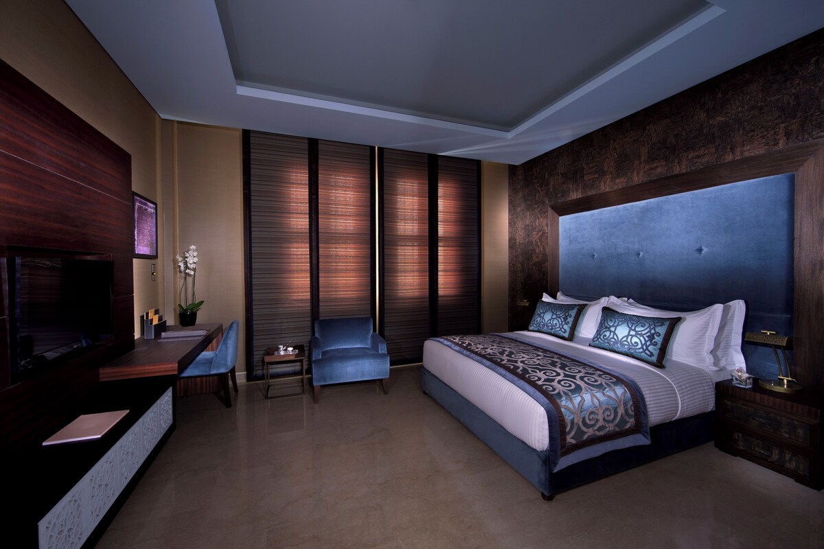 Una habitación de hotel moderna con una cama grande, un escritorio y una zona de estar.