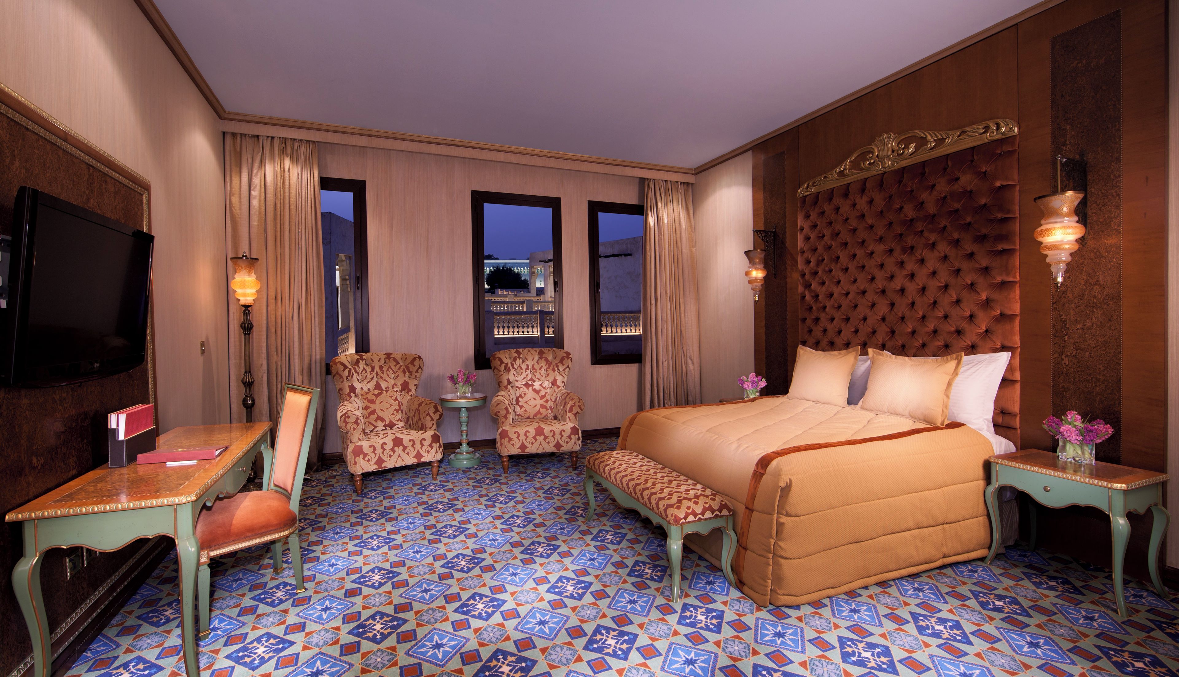 Een hotelkamer met een groot bed, twee fauteuils, een bijzettafeltje en een televisie.