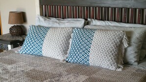A bed with a patterned bedspread and multiple pillows, including a blue and white patterned pillow and a white textured pillow. - Meerkat Manor (Nkomazi)