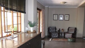 A spacious living area with a kitchen counter, two armchairs, a coffee table, and a decorative rug. - Meerkat Manor (Nkomazi)