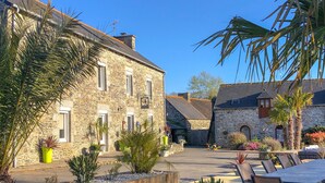 A stone building with a courtyard, potted plants, and outdoor seating. - Domaine du Grenier (Yffiniac)