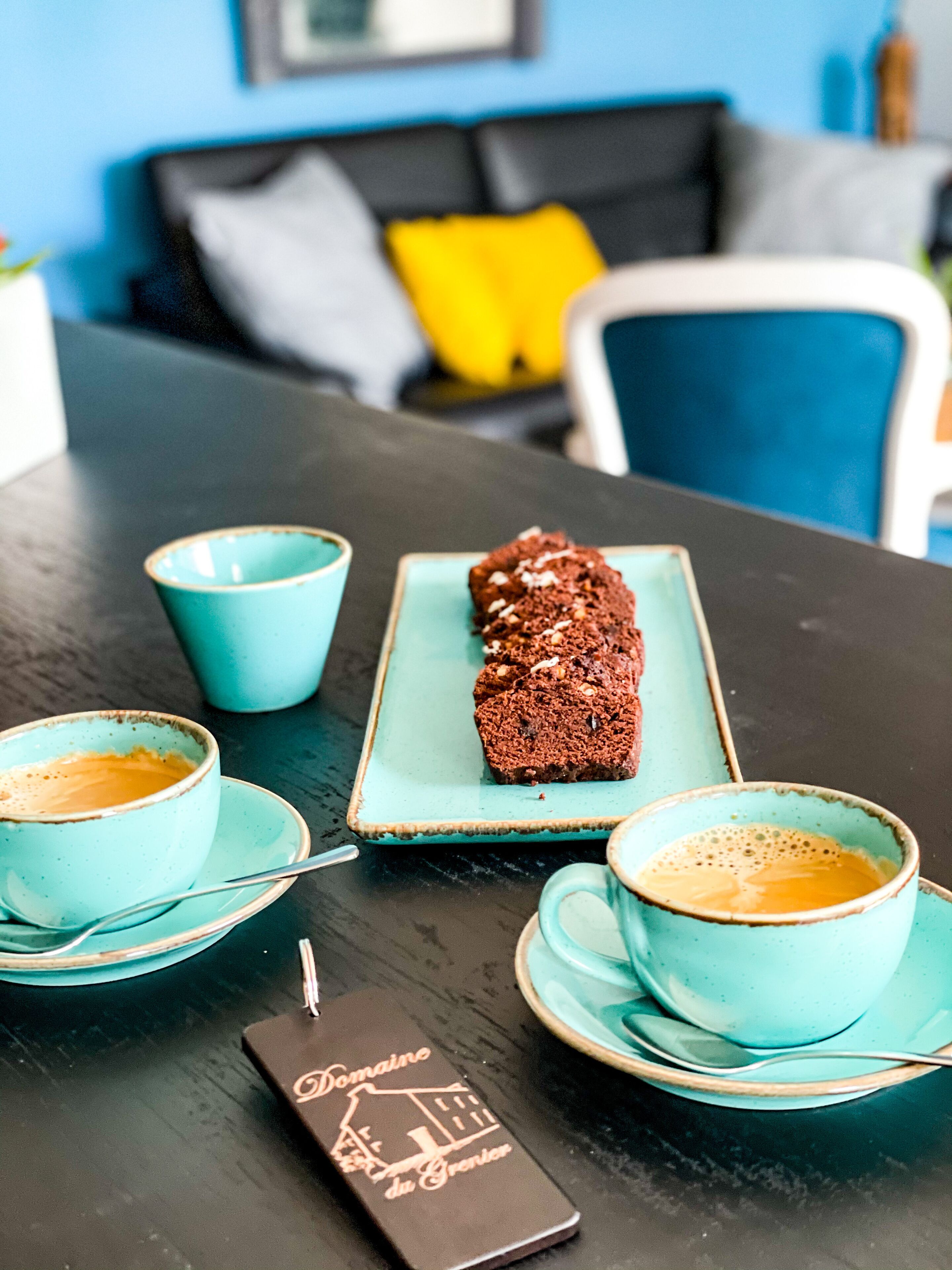 Une table avec deux tasses de café, une assiette avec une miche de pain et un panneau posé sur la table.