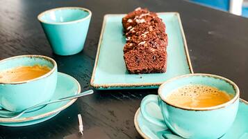 Une table avec deux tasses de café, une assiette avec une miche de pain et un panneau posé sur la table.