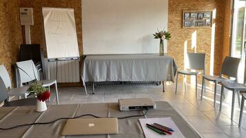 A conference room with a wooden ceiling, a whiteboard, a projector, a laptop, and a table with chairs.