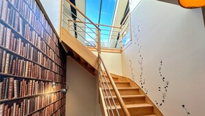 A library with wooden stairs and a skylight. - Domaine du Grenier (Yffiniac)