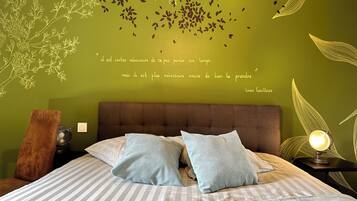 Un dormitorio con pared verde, cama con ropa de cama a rayas y una cita decorativa de Louis Guillaum.