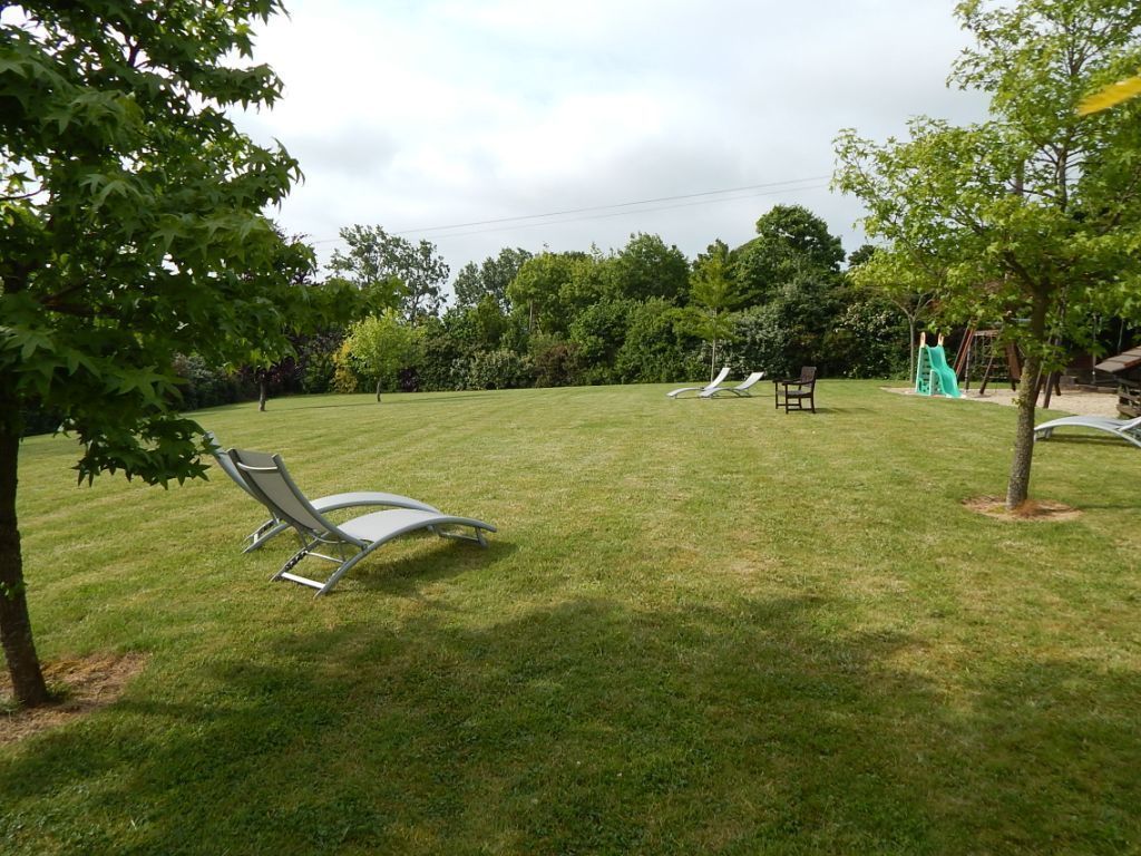 Un espace extérieur verdoyant avec deux chaises longues et un petit arbre.