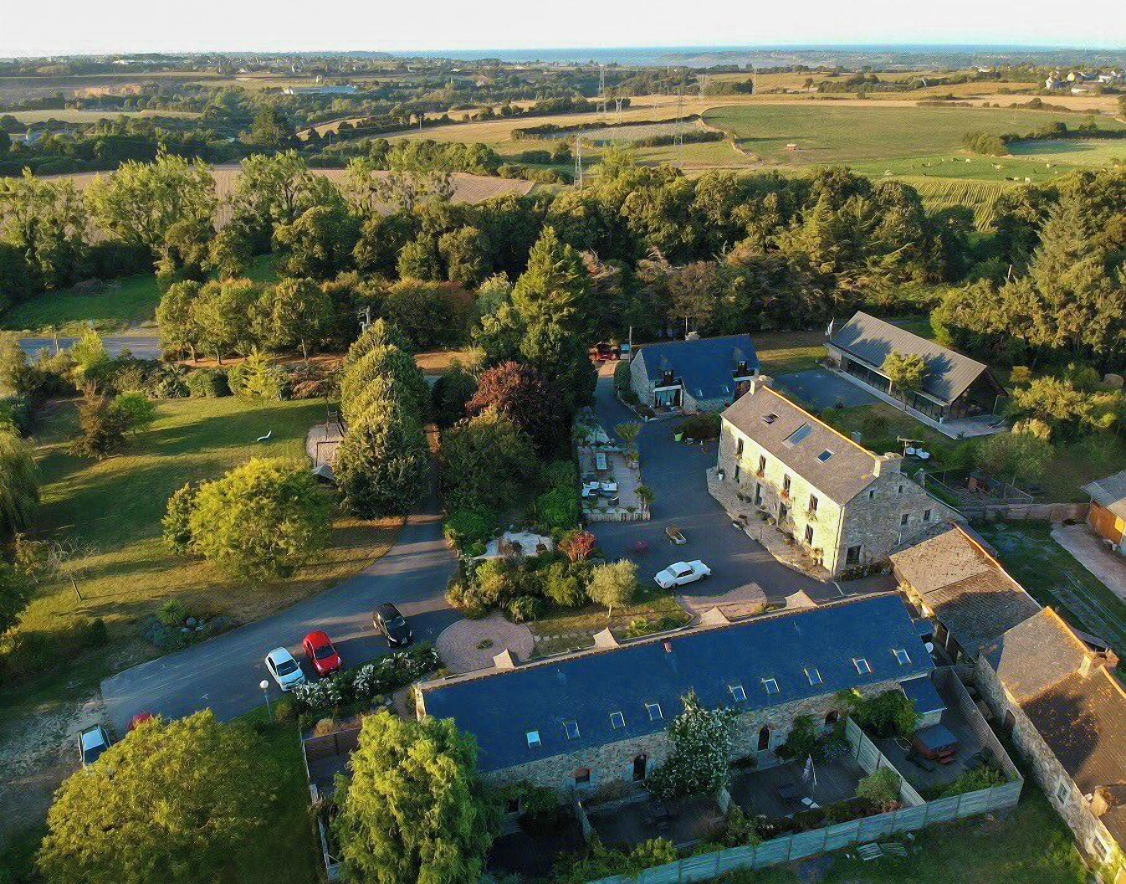 An aerial view of a rural property with a main building, guest rooms, and a swimming pool.