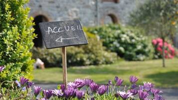 A sign with the word "ACCEIL" and an arrow pointing to the right, placed in front of a building with a stone facade and arched windows.