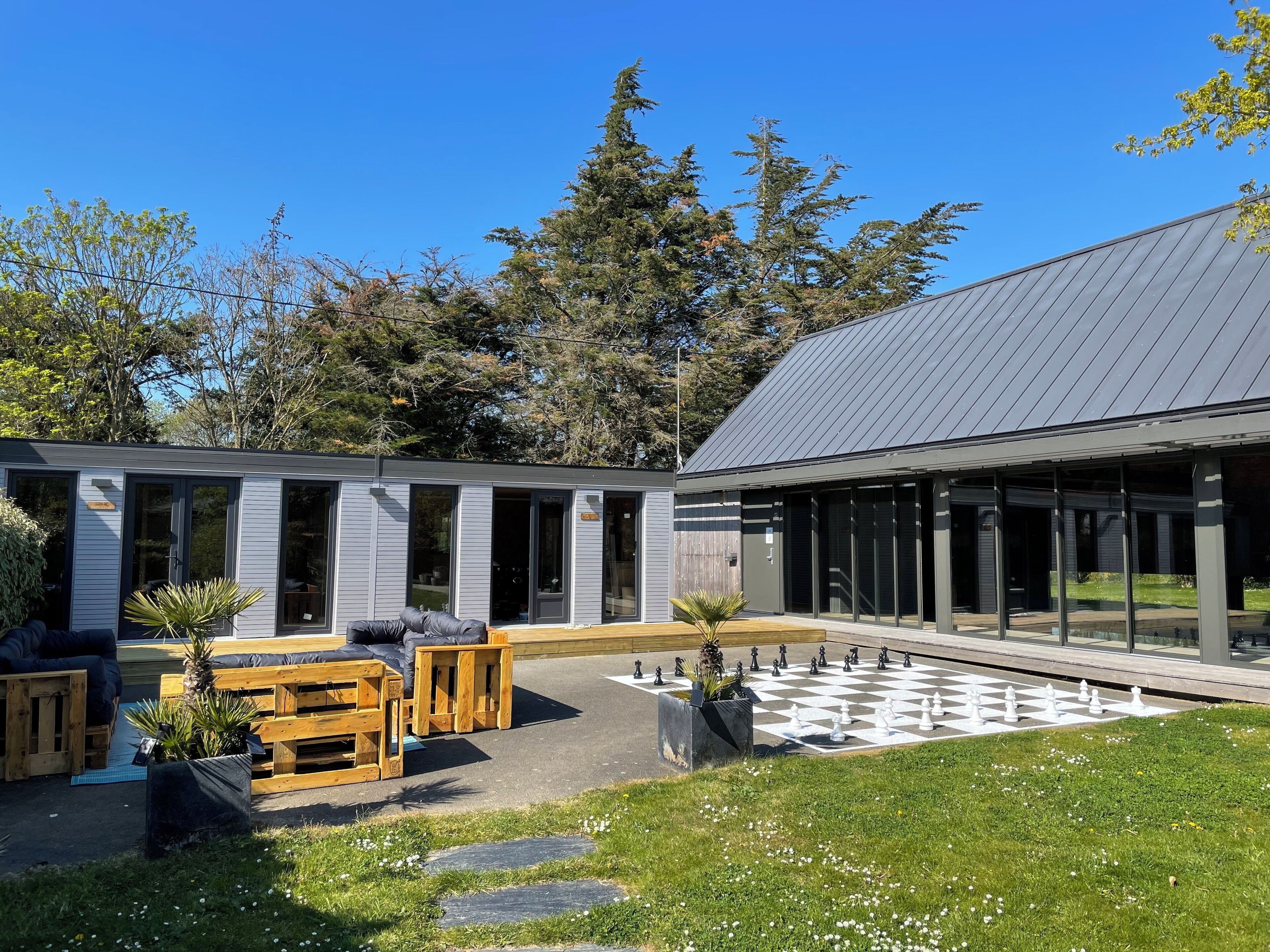 A modern building with large windows and a courtyard with a chessboard.