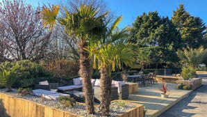 A garden area with wooden planters, seating, and a variety of plants. - Gîtes Domaine du Grenier (Yffiniac)