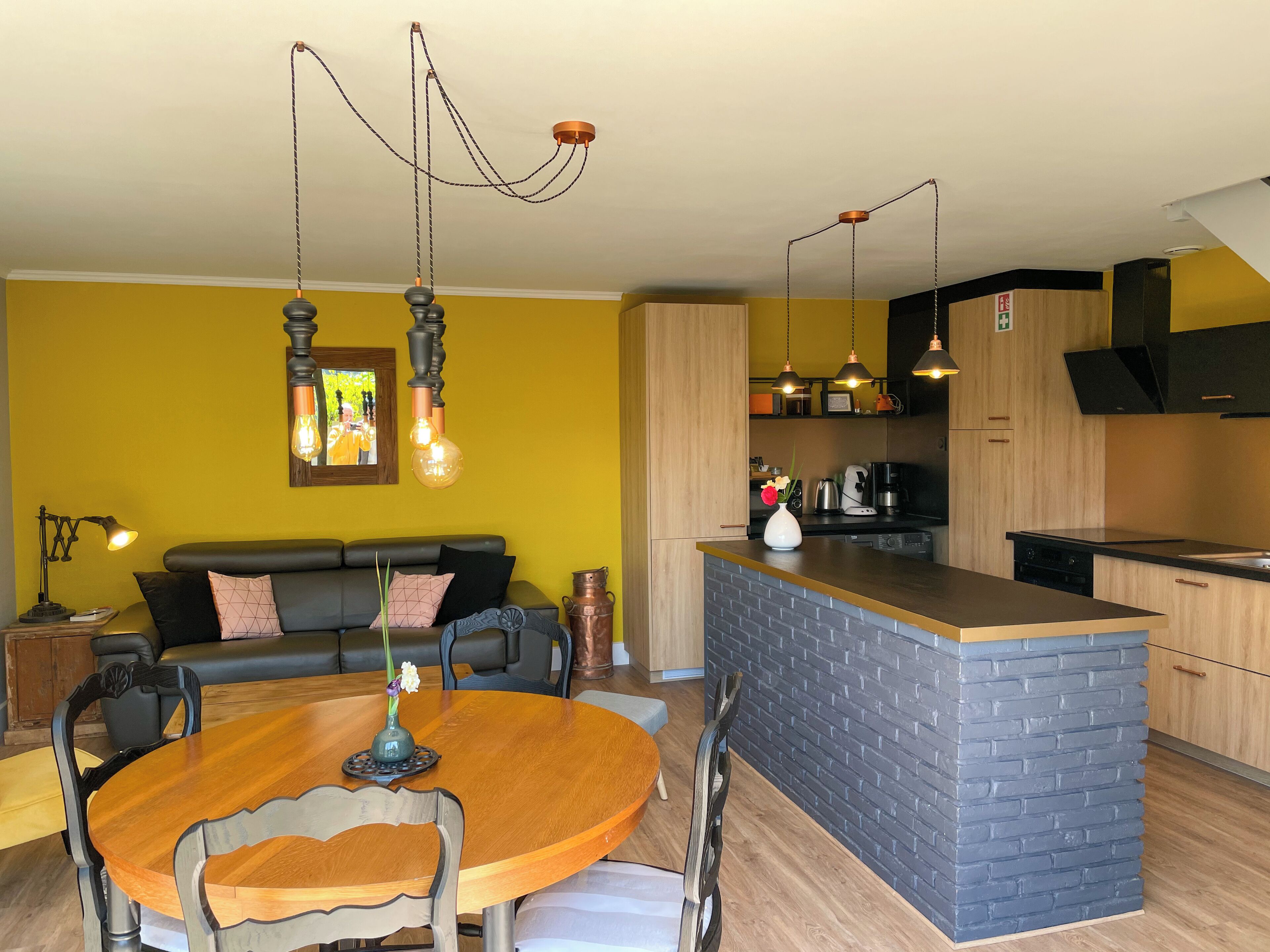 A modern kitchen with a central island, a dining area with a wooden table and chairs, and a living area with a sofa and a coffee table.