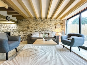 Una sala de estar acogedora con pared de piedra, techo de madera y un ventanal grande.