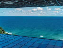 A view of the ocean from a covered area with a metal roof.