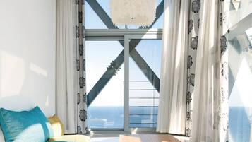 Ein Zimmer mit großem Fenster, Deckenventilator in Weiß und Blick auf den Ozean.