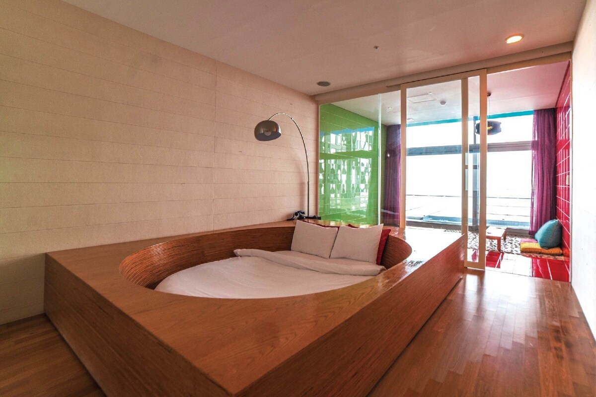 Une chambre moderne dotée d’une grande baignoire en bois, d’une porte vitrée donnant sur l’extérieur et offrant une vue sur le paysage.