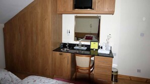 A bedroom with a wooden wardrobe, a desk with a chair, a television, and a mirror. - Fortview House Bed & Breakfast (Belturbet)
