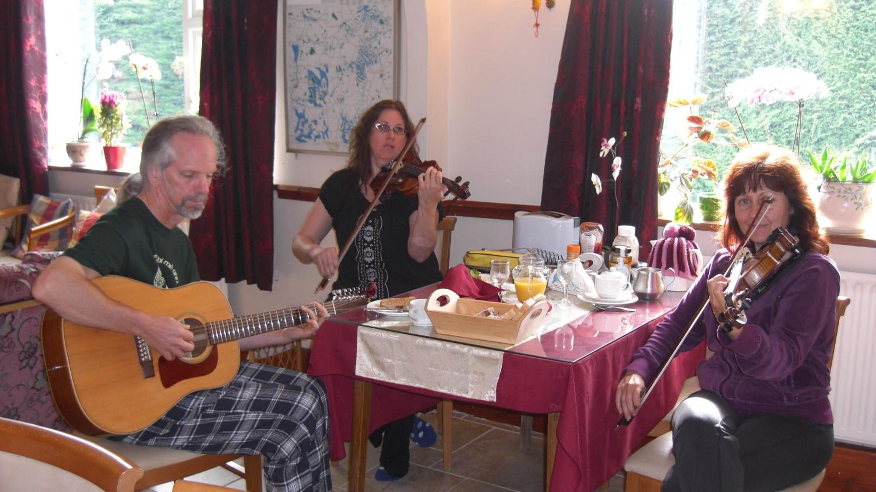 A dining area with a table set for breakfast, featuring a guitar player, a violinist, and a person with a violin.