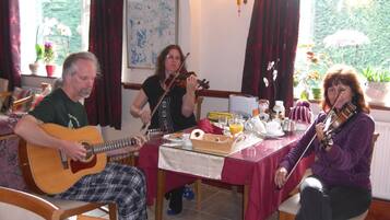 A dining area with a table set for breakfast, featuring a guitar player, a violinist, and a person with a violin.