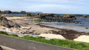 A coastal landscape with rocky outcrops, sandy beach, and a clear sky. - Garron View Bed and Breakfast (Ballymena)