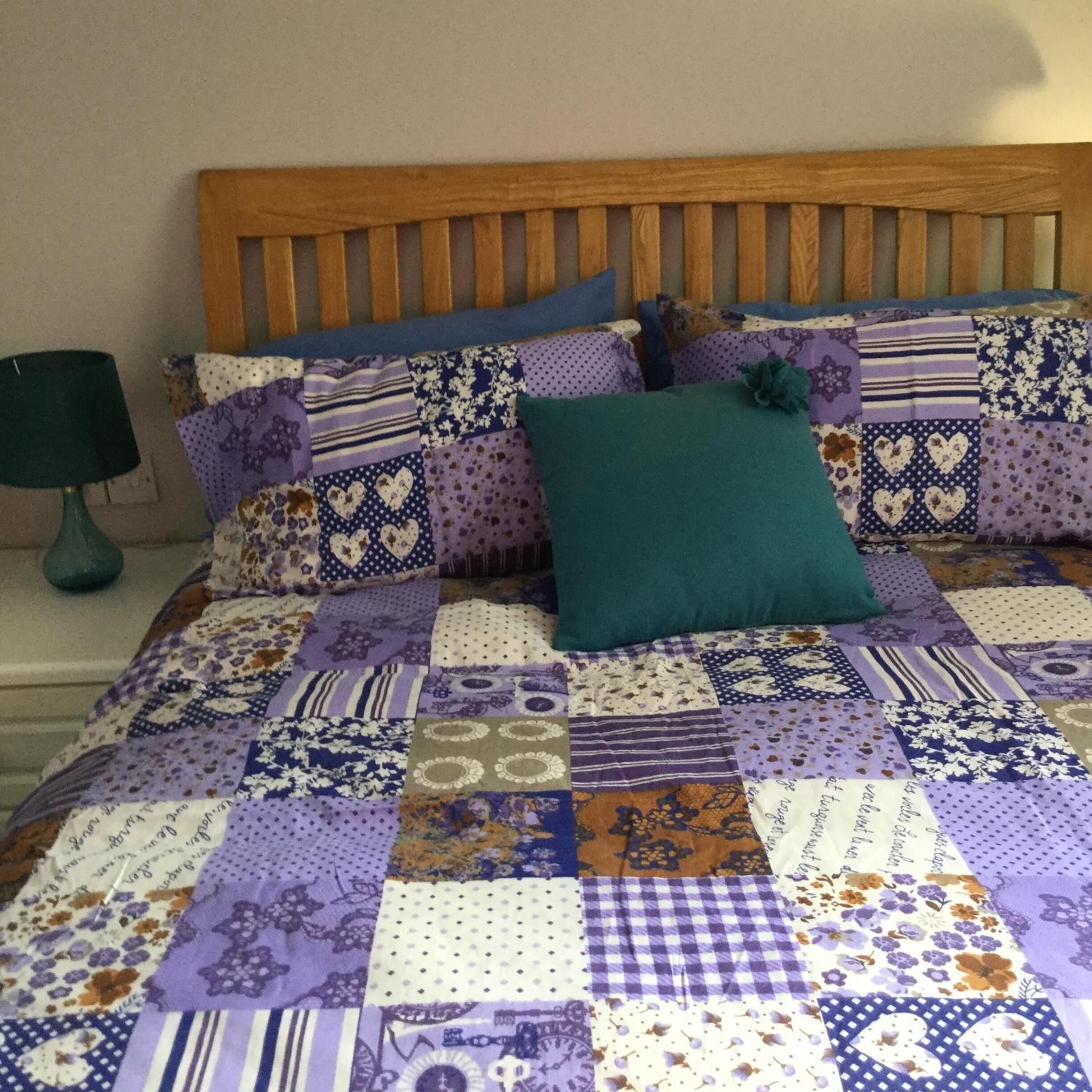A bed with a patchwork quilt and several pillows.