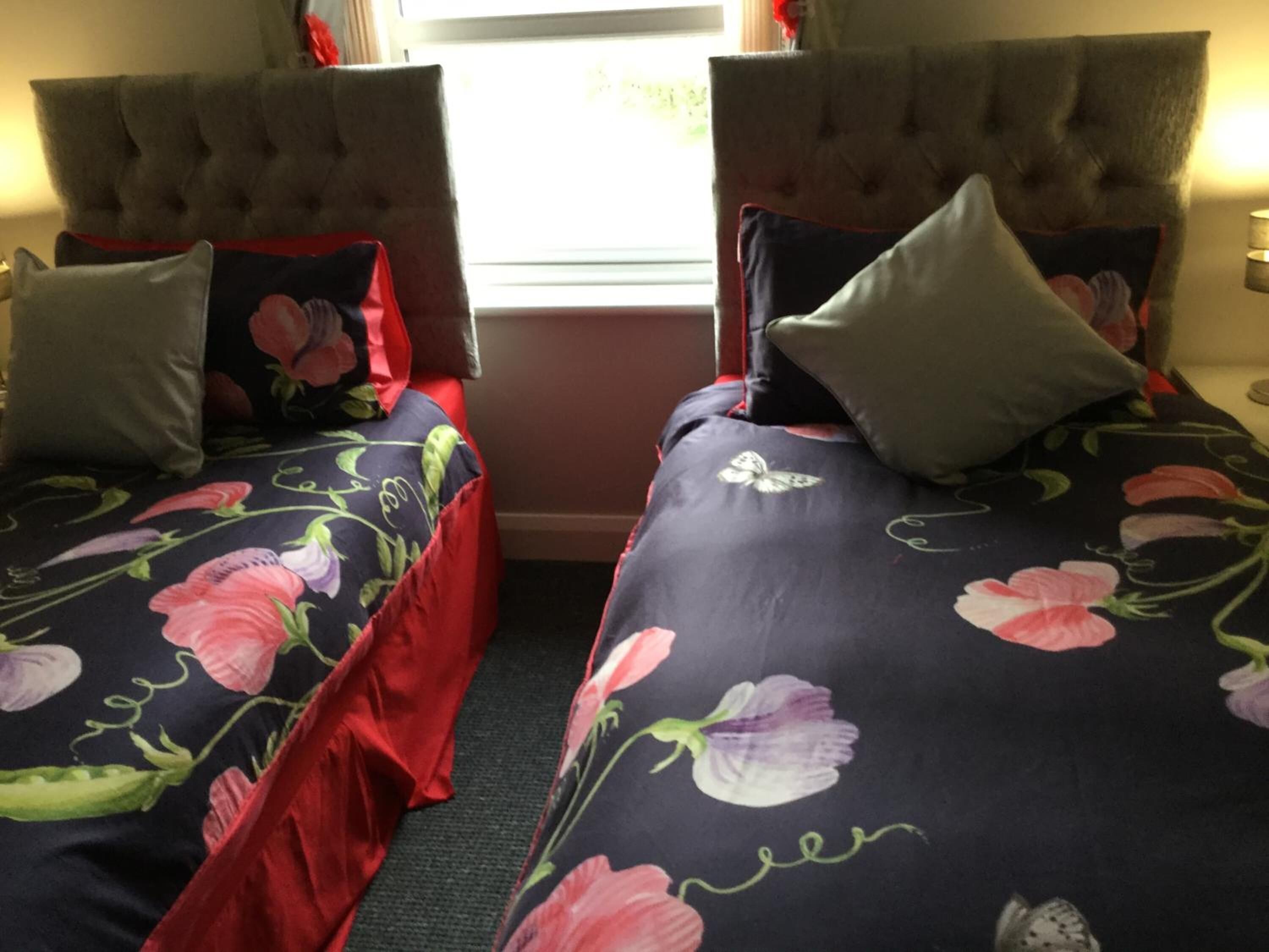 Two twin beds with floral bedding, tufted headboards, and matching pillows.