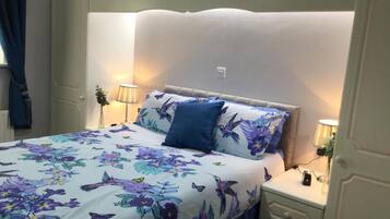 A neatly made bed with floral bedding, two bedside lamps, and a nightstand with a lamp.
