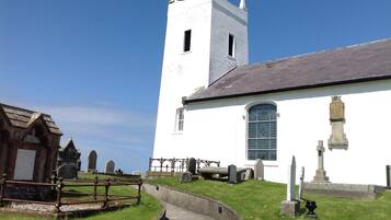 A white church with a bell tower and a cemetery in the foreground.