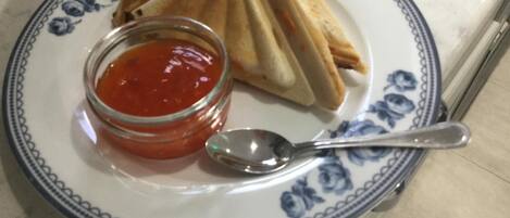 Un plato con un sándwich y un frasco pequeño de salsa, acompañado de una cuchara.