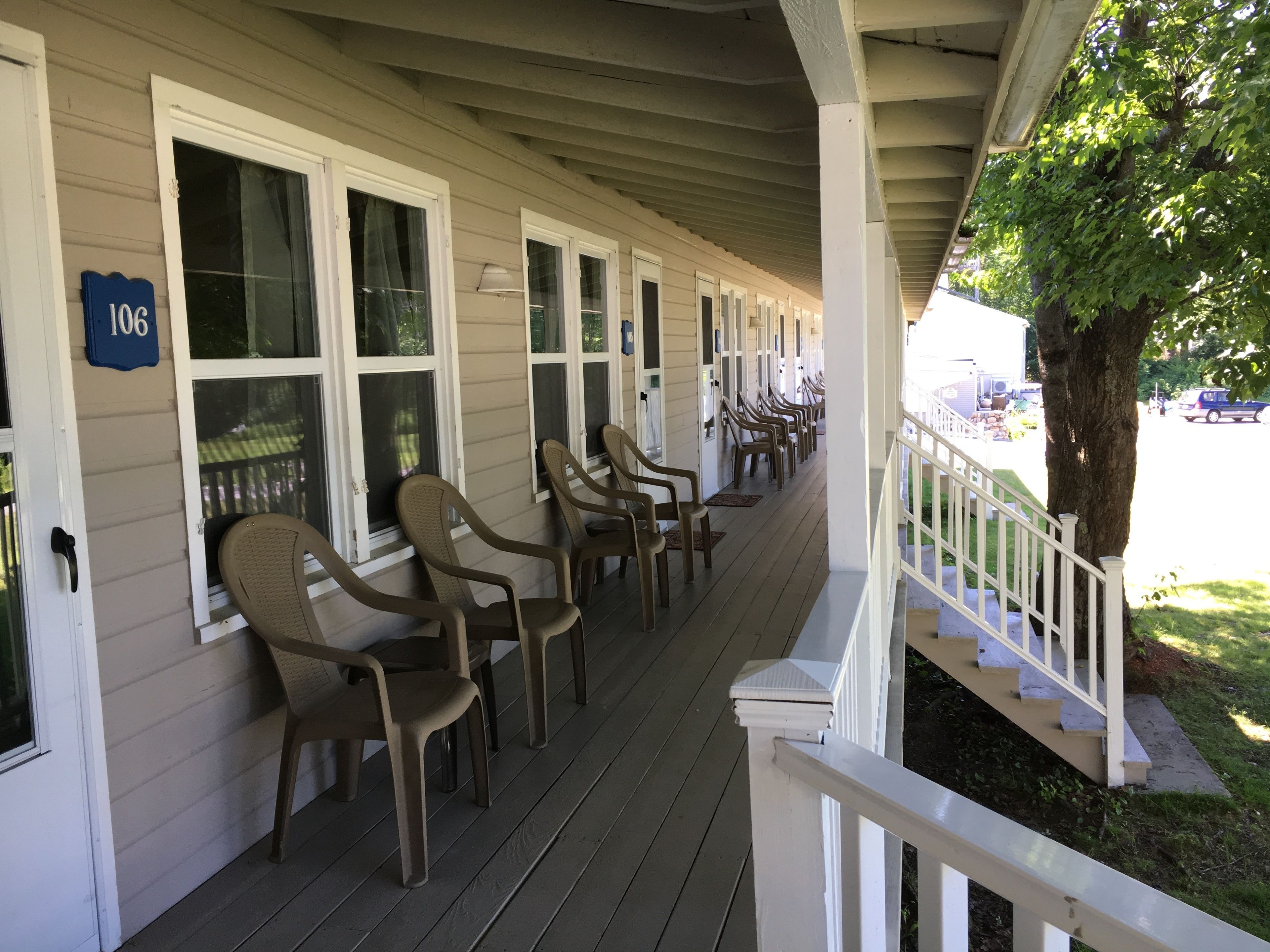 A covered porch with rows of plastic chairs and a white railing.